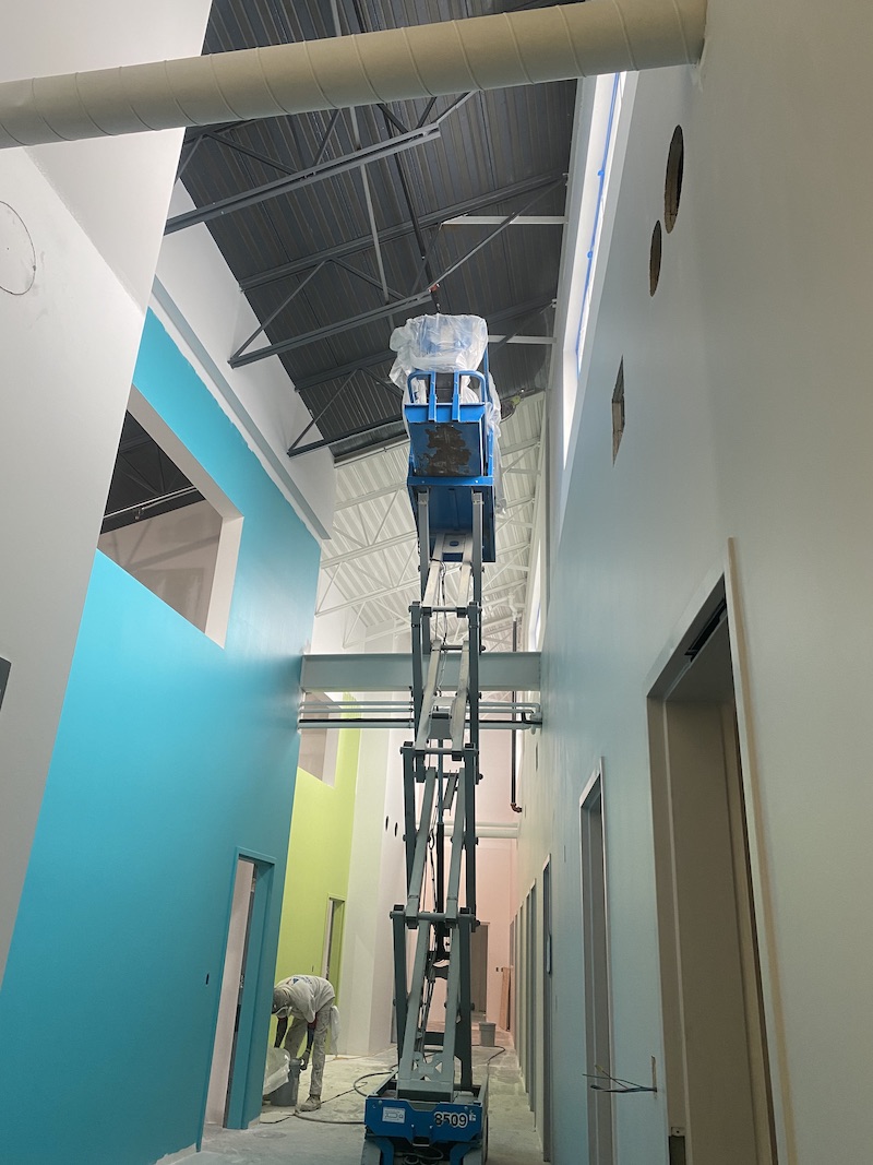 Photo of Logan painter working next to scissor lift inside a building